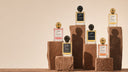 Collection of Perfucio's perfume bottles on stone plinths against a beige background